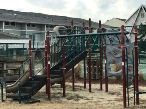 A playground with a slide and climbing structure designed to resemble an elephant, set against a cloudy sky.