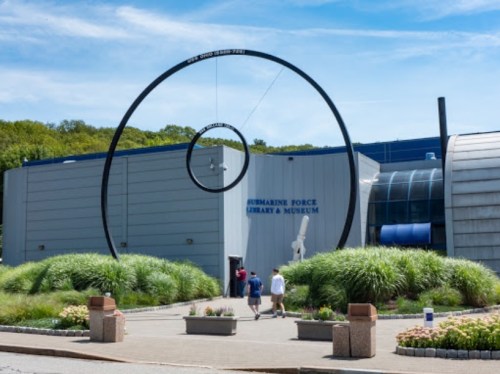 Entrance to the Submarine Force Library and Museum, featuring a large circular sculpture and lush greenery.