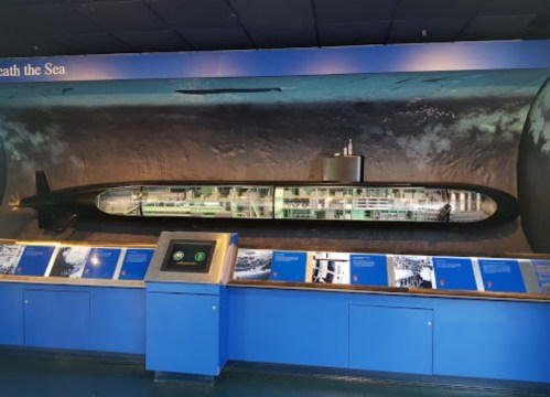 A large model of a submarine displayed against a blue wall, with informational panels below.