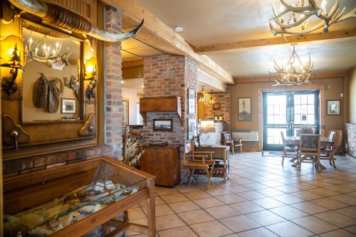 Cozy interior of a rustic lodge with wooden furniture, antler decor, and a welcoming entrance.