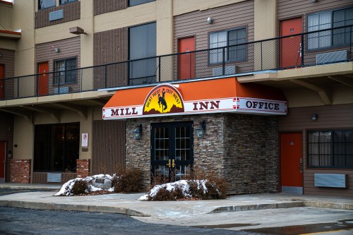 Exterior of the Mill Inn office, featuring a stone facade and orange awning, with snow on the ground.