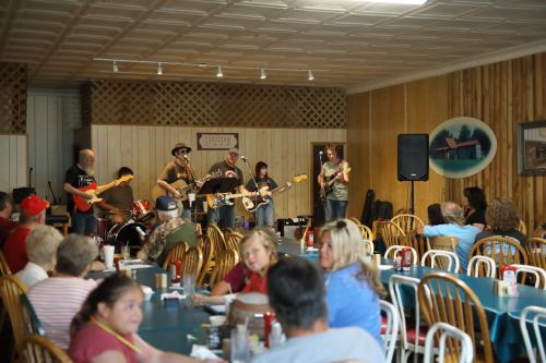 A live band performs on stage in a cozy restaurant, while patrons enjoy their meals at tables.