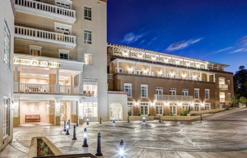 Exterior view of Drury Plaza Hotel at night, featuring illuminated pathways and a modern architectural design.
