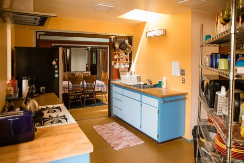Bright kitchen with blue cabinets, wooden countertops, and a dining area in the background. Cozy and inviting atmosphere.