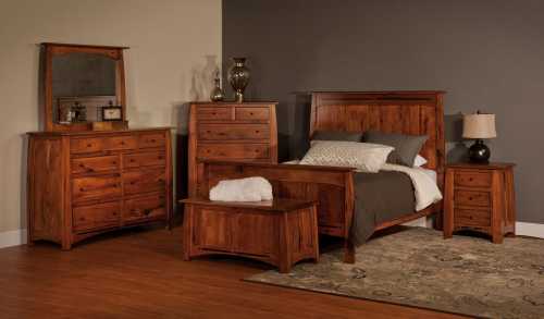 A cozy bedroom set featuring a wooden bed, nightstands, dresser, and mirror against a neutral wall.