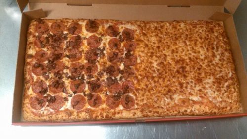 A large rectangular pizza with pepperoni on one side and cheese-only on the other, in a pizza box.