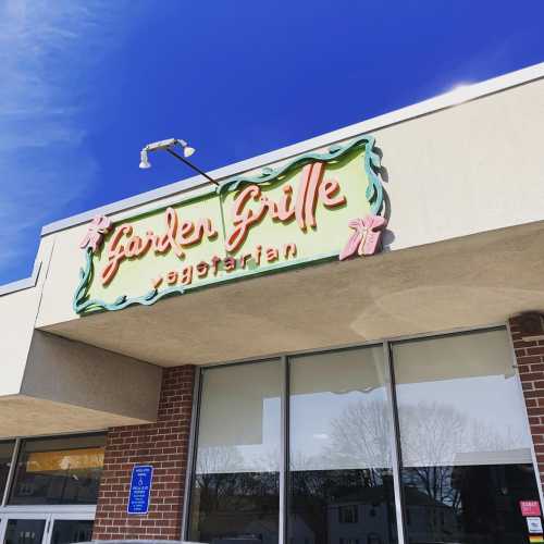 Sign for "Garden Grille Vegetarian" against a clear blue sky, with a brick building below.