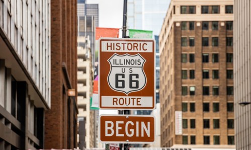 Sign for Historic Route 66, marking the beginning of the iconic highway in an urban setting.