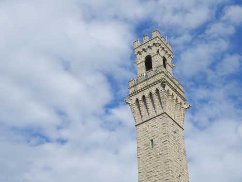 A tall stone tower against a backdrop of blue sky and fluffy white clouds.