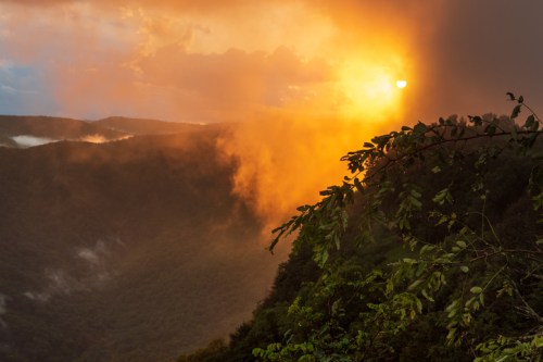 A stunning sunset over misty mountains, with vibrant orange and yellow hues illuminating the sky.