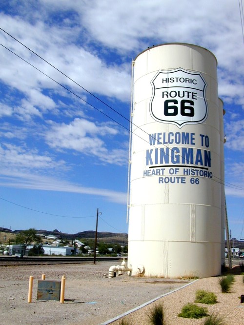 A large water tower with "Welcome to Kingman" and "Historic Route 66" painted on it, set against a blue sky.