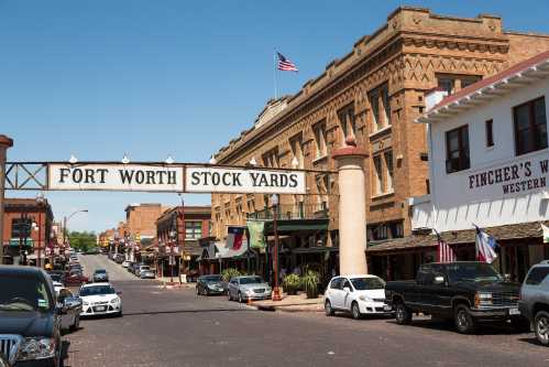 A street view of Fort Worth Stockyards, featuring historic buildings and a large sign overhead.