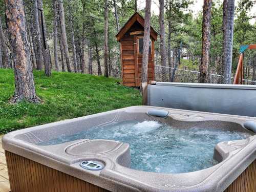 A hot tub with bubbling water surrounded by trees and a wooden shed in a serene outdoor setting.