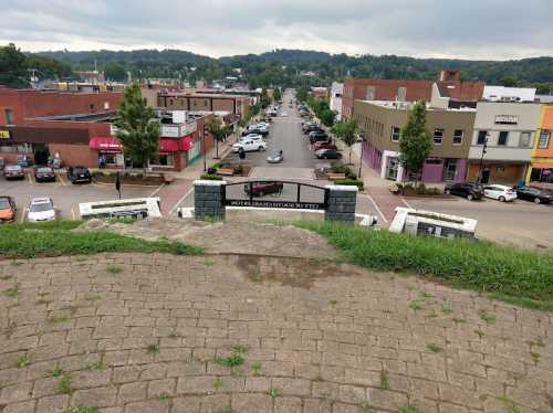 View from a hilltop overlooking a street lined with shops and parked cars, with a sign for "Grandview Park."