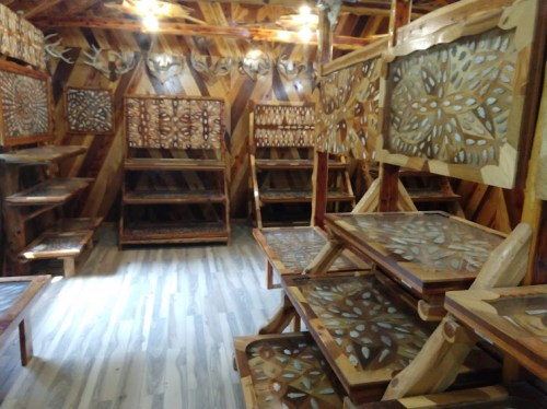 A wooden interior featuring intricately carved shelves and tables, showcasing a rustic and artistic design.
