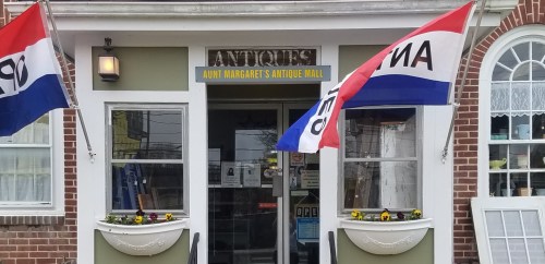 Front view of Aunt Margaret's Antique Mall, featuring flags and a welcoming entrance with flower planters.