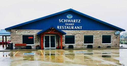 A blue and brick restaurant building with "Schwartz Family Restaurant" sign and an "Open" sign in the window.
