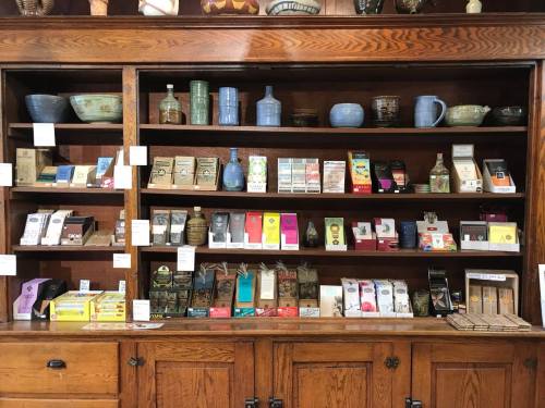 A wooden shelf displaying various packaged goods, including snacks, drinks, and decorative items.