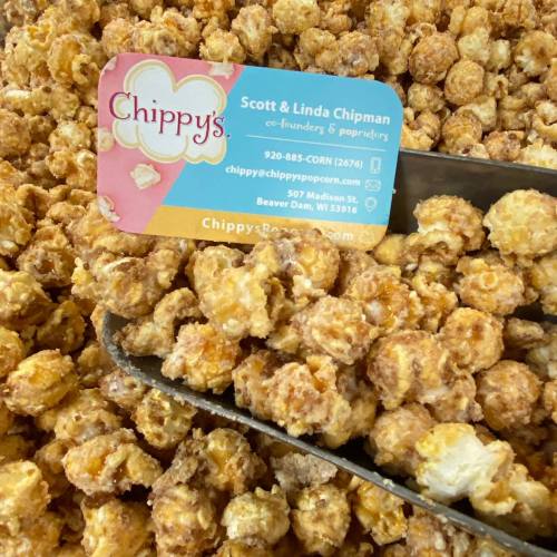 A scoop of popcorn next to a business card for Chippy's, featuring founders Scott and Linda Chipman.