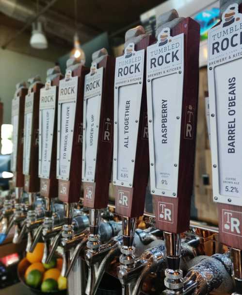 A row of beer taps with labels for various brews at Tumbled Rock Brewery Kitchen.