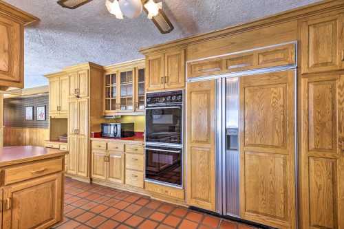 A spacious kitchen featuring wooden cabinets, a double-door refrigerator, and built-in appliances on a tiled floor.