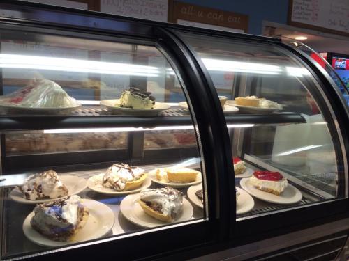 A display case filled with various slices of pie on plates, including cream and fruit-topped options.