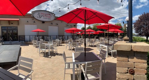 Outdoor dining area with red umbrellas, tables, and chairs, set against a cloudy sky.