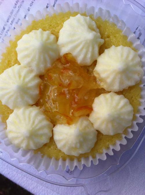 A yellow dessert topped with cream swirls and a glossy fruit filling in the center, arranged like a flower.