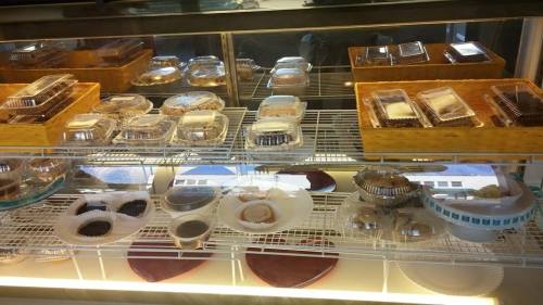 Display case filled with various desserts in clear containers, showcasing cakes, pastries, and other sweet treats.