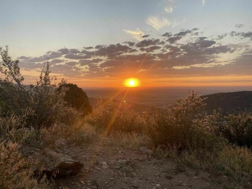 A stunning sunset over a mountainous landscape, with vibrant colors and clouds in the sky.