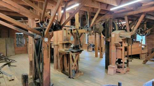 Interior of a wooden workshop with various tools and machinery, showcasing exposed beams and a rustic atmosphere.