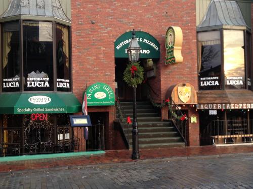 A brick building with multiple restaurant signs, festive decorations, and an open entrance to a pizzeria.