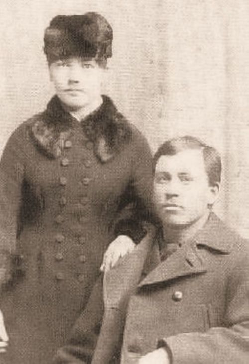 A vintage black-and-white photo of a man and woman, both dressed in formal attire, posing together.