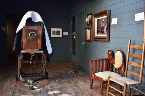 A vintage camera covered with a cloth in a room with wooden floors and antique furniture.