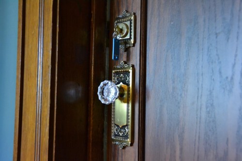 A close-up of an ornate door handle with a crystal knob and a key in the lock on a wooden door.