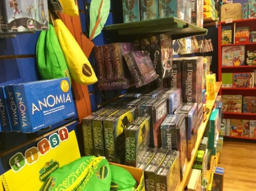 A colorful display of board games and toys on shelves in a store, featuring various game boxes and vibrant merchandise.