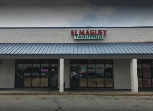 Exterior of El Maguey Taqueria, featuring a sign and large windows, located in a shopping plaza.