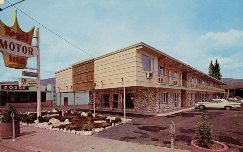 A vintage motel with a stone facade, sign reading "Royal Motor Inn," and parked cars in a sunny setting.