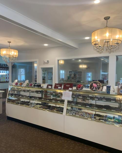 A bright shop interior featuring a display case filled with various items, illuminated by stylish chandeliers.