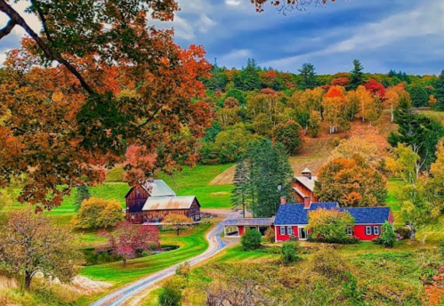 A scenic autumn landscape featuring a red farmhouse, barn, and colorful trees along a winding road.