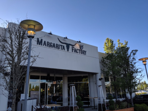Exterior of the Margarita Factory restaurant, featuring a large sign with a bull and palm tree logo.