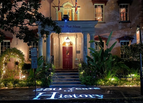 The Olde Pink House restaurant, illuminated at night, with "350 Years of History" projected on the ground.