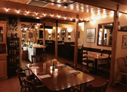 Cozy restaurant interior with wooden tables, soft lighting, and decorative artwork on the walls.