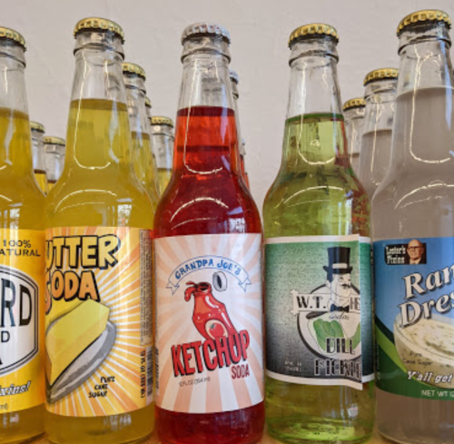 A variety of colorful soda bottles, including butter, ketchup, and ranch flavors, displayed on a shelf.