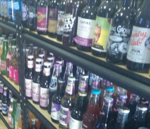 A variety of colorful soda bottles lined up on shelves, showcasing different brands and flavors.