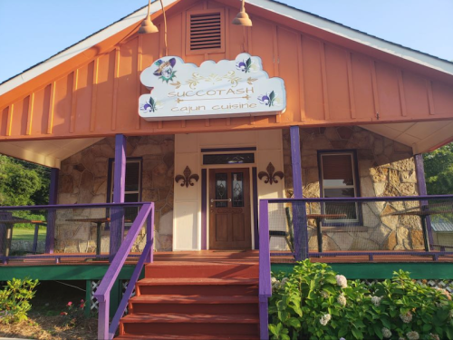 A colorful restaurant with a sign reading "Succotash Cajun Cuisine" and a welcoming front porch.