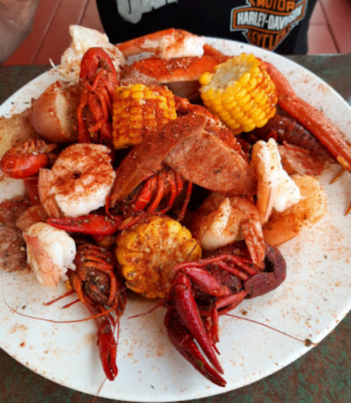 A plate of seafood featuring crawfish, shrimp, corn, and various spices, served on a table.