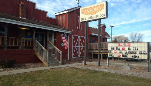 Exterior of Anson's Grill, Pizza, and Saloon with a sign advertising events and an American flag.