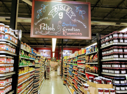Aisle in a grocery store labeled "Aisle 9" featuring Polish, Serbian, Croatian, and Romanian products on shelves.