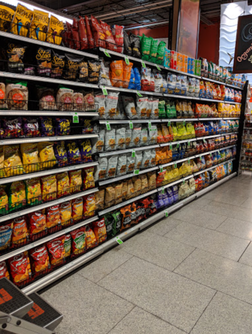 A grocery store aisle filled with various snack bags, including chips and popcorn, neatly arranged on shelves.